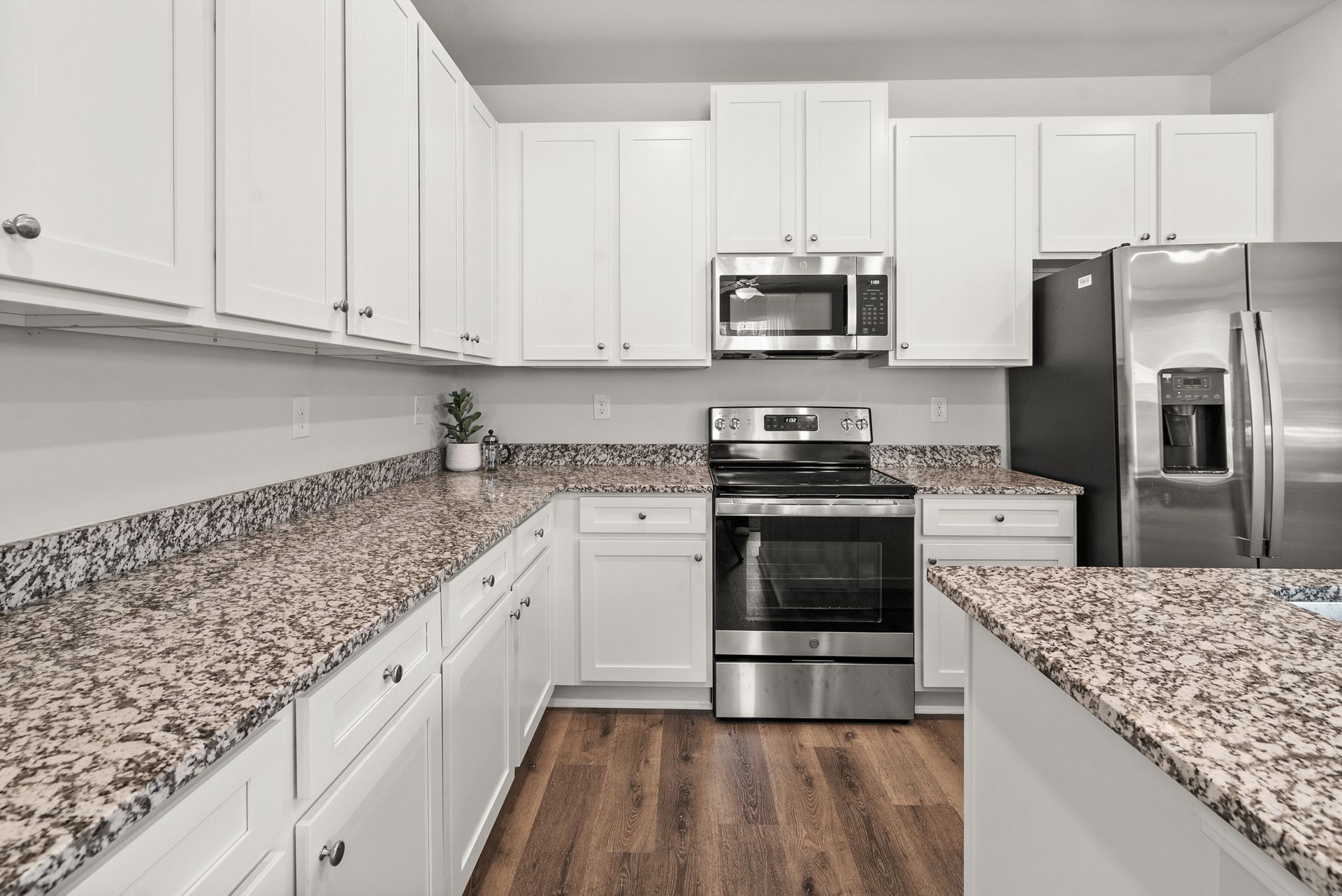 A kitchen with granite counter tops , stainless steel appliances , and white cabinets.