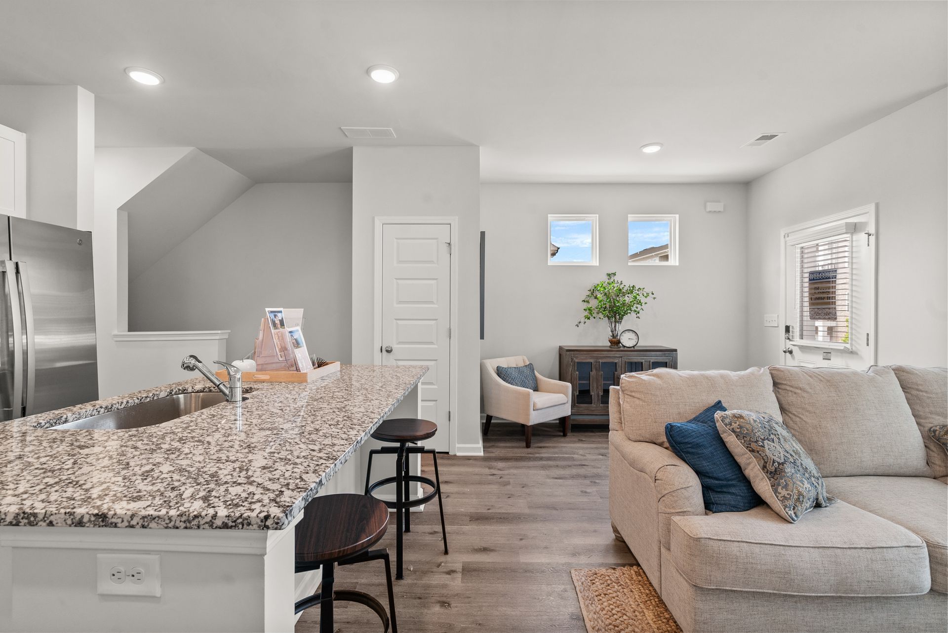 A living room with a couch and a kitchen with a granite counter top.