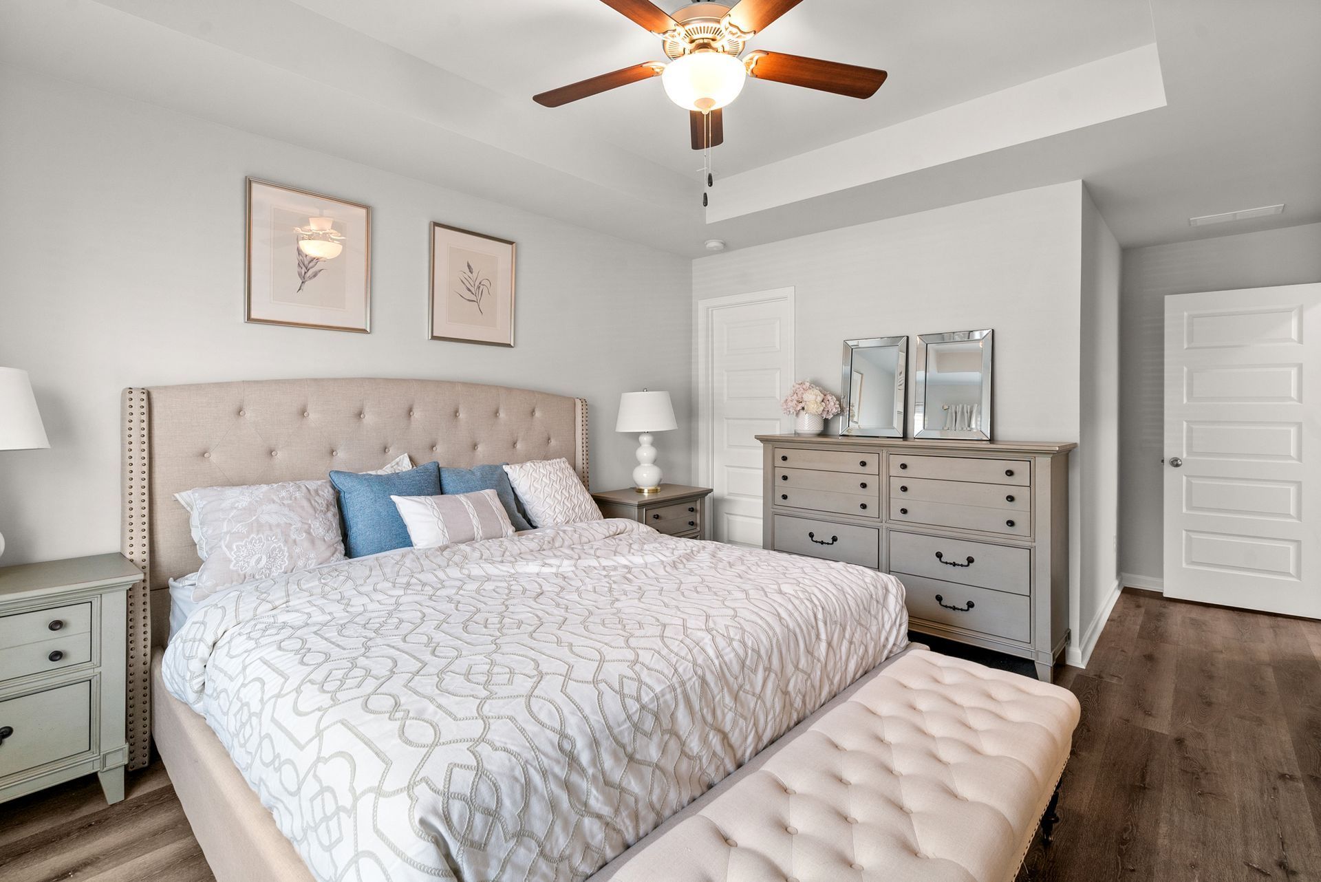 A bedroom with a bed , dresser , nightstand and ceiling fan.