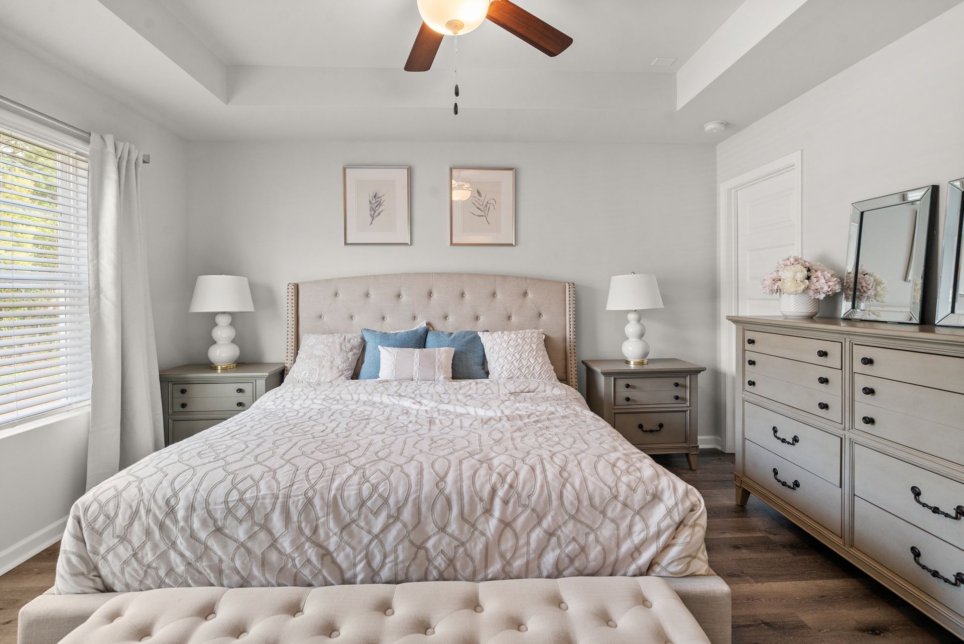 A bedroom with a bed , dresser , nightstand , and ceiling fan.