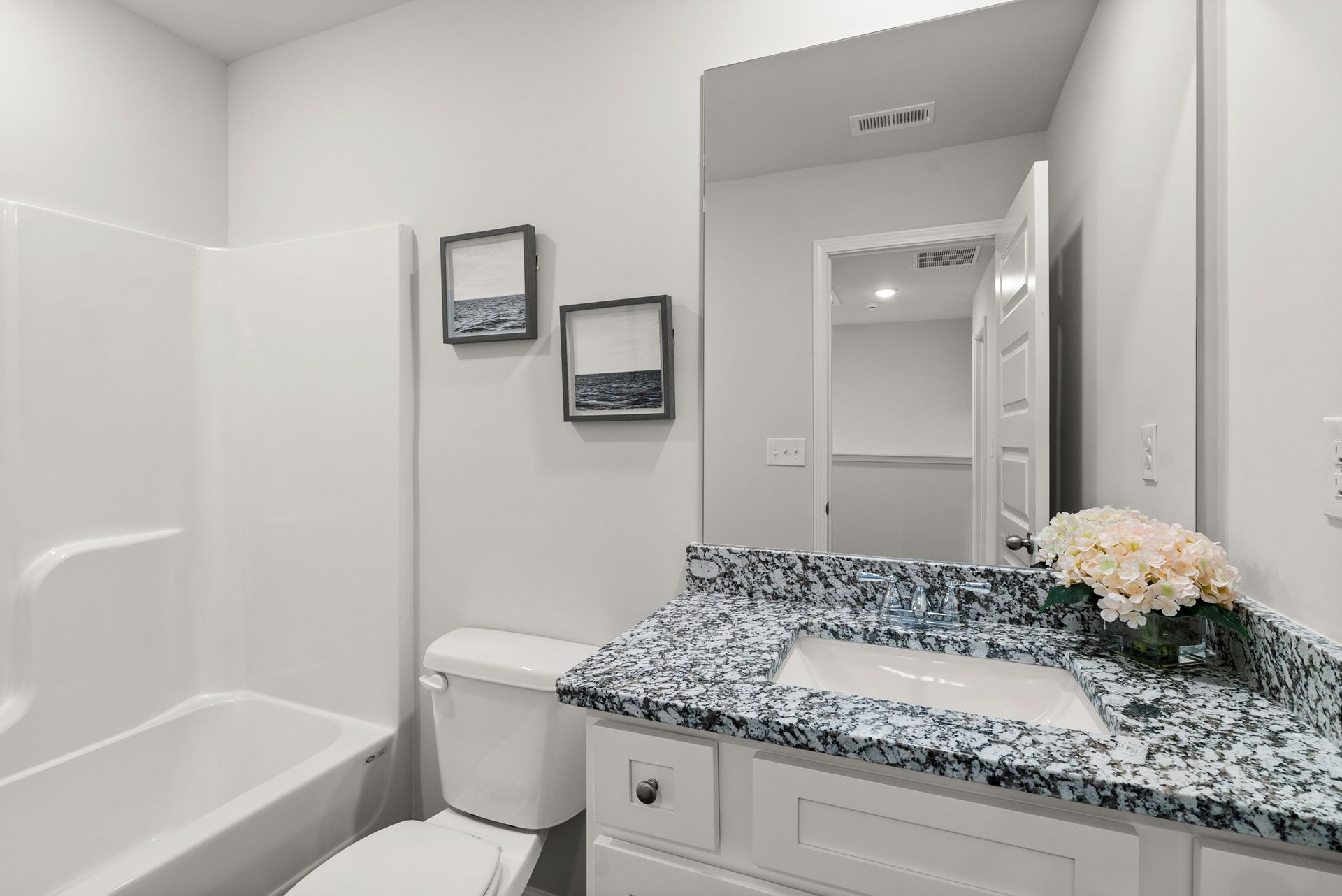 A bathroom with a toilet , sink , bathtub and mirror.