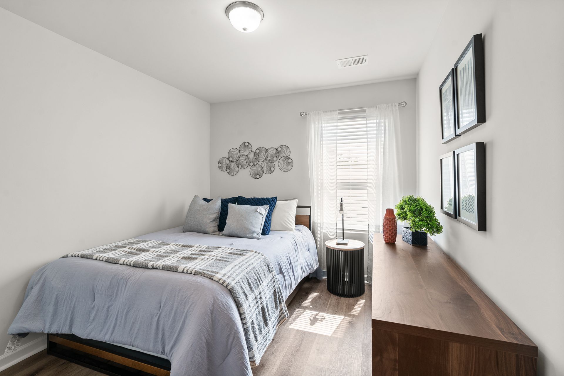 A bedroom with a bed , dresser , and window.