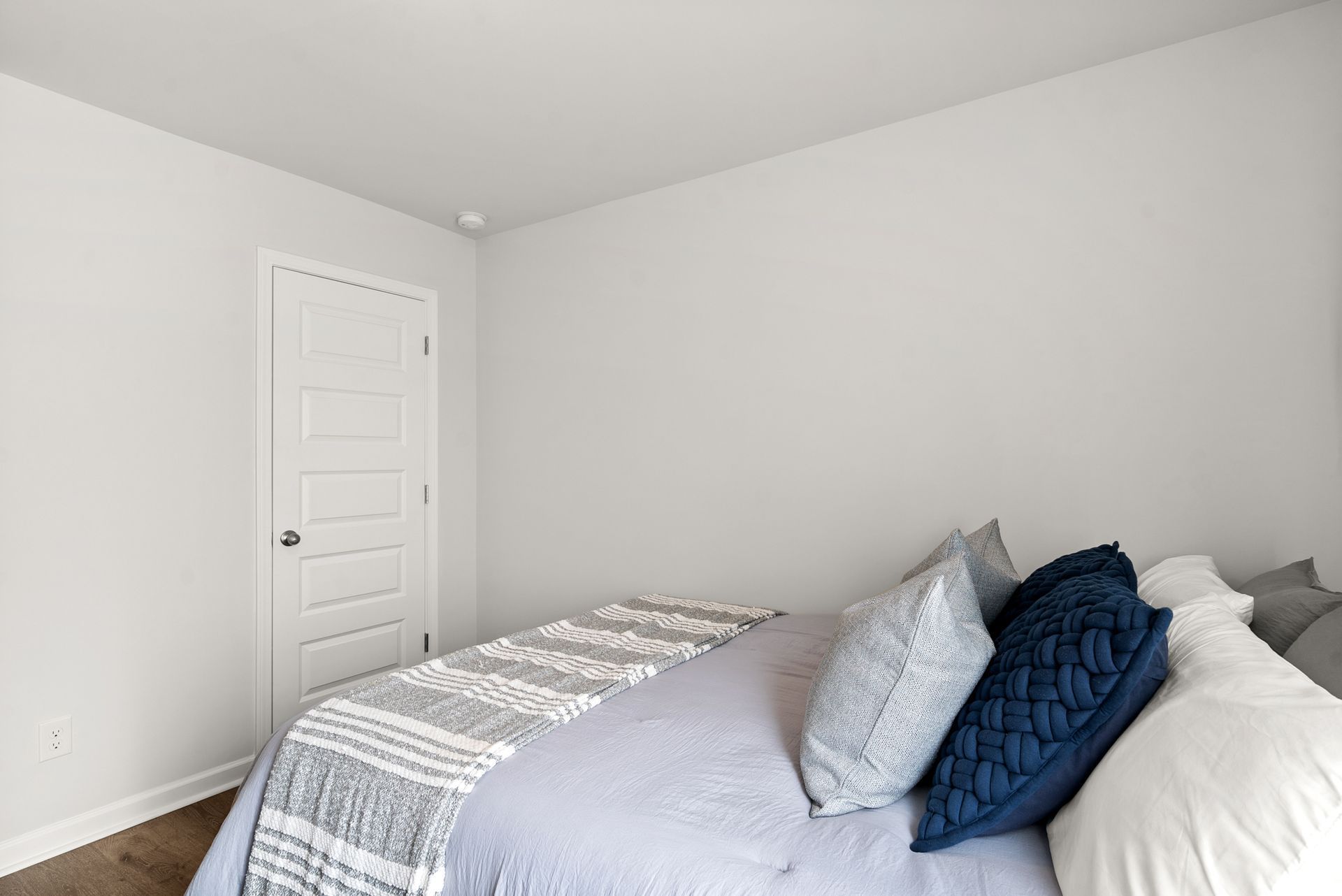 A bedroom with a bed , pillows and a door.