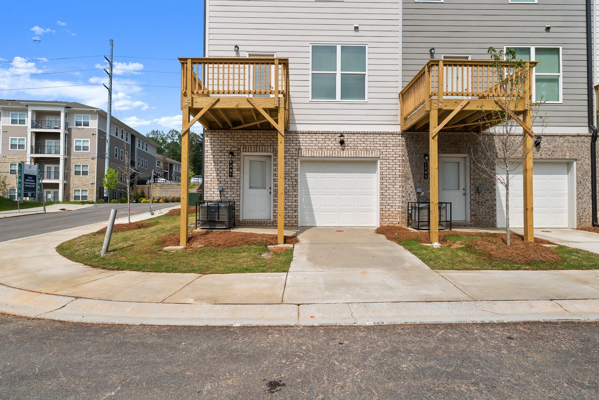 The front of a house with a wooden deck and two garages.