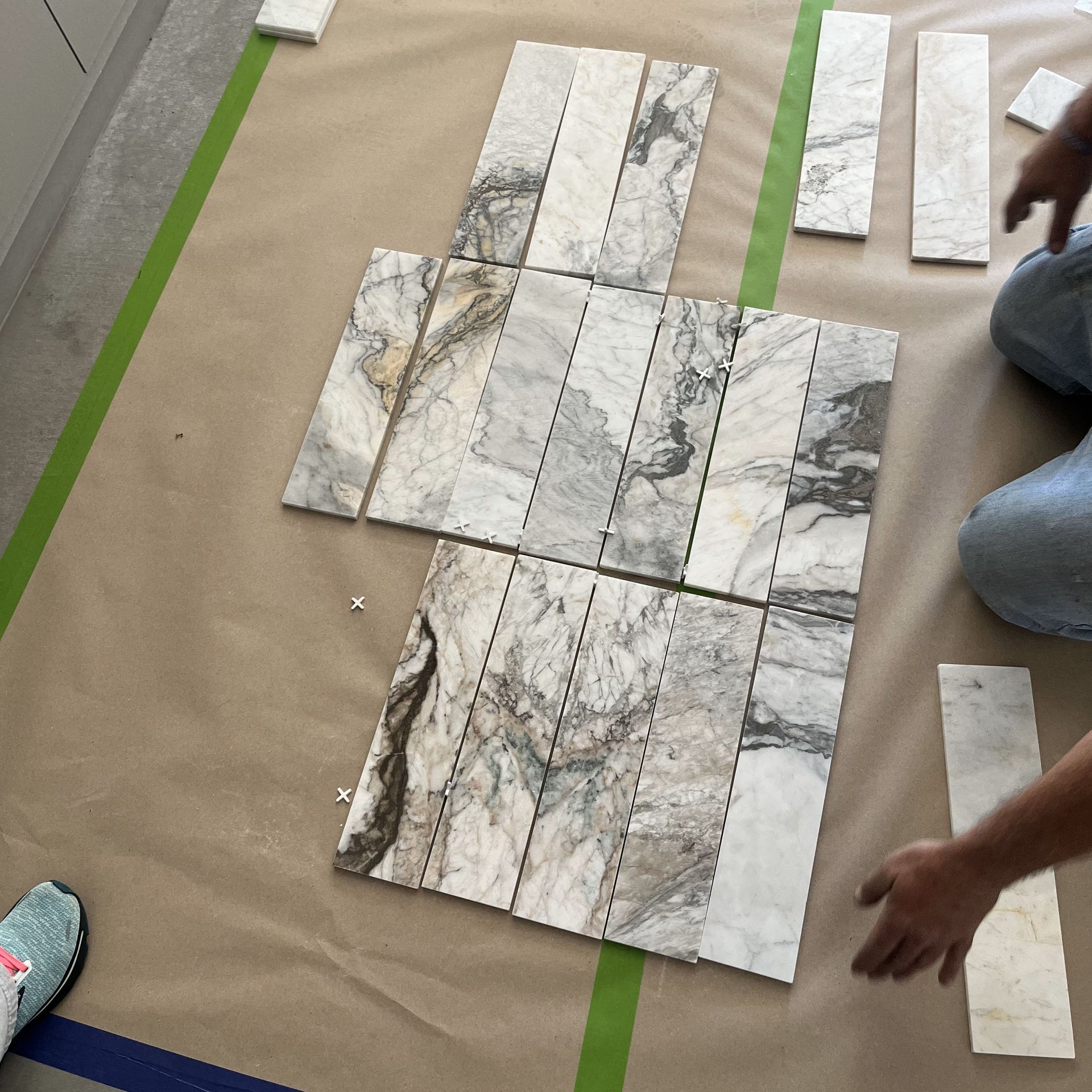 A person is laying marble tiles on a table