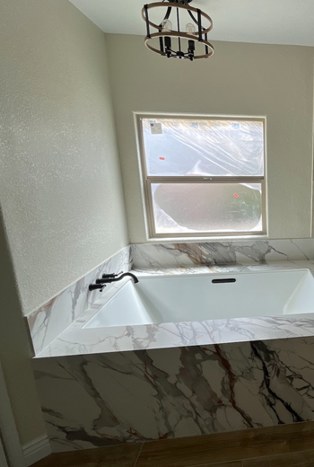 A bathroom with a bathtub and a window.