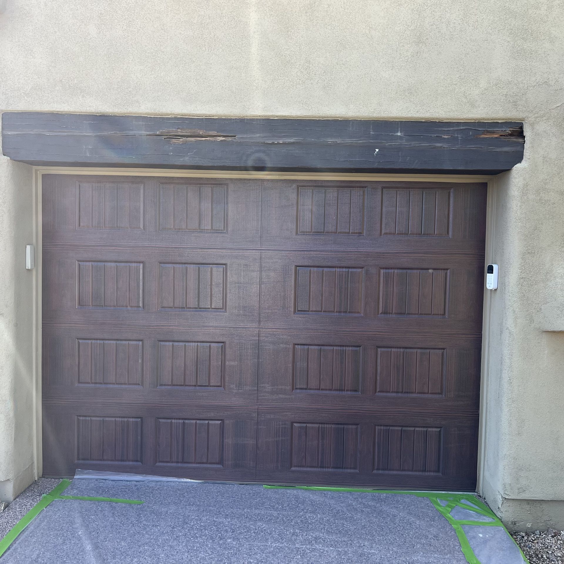 A brown garage door with a black beam above it