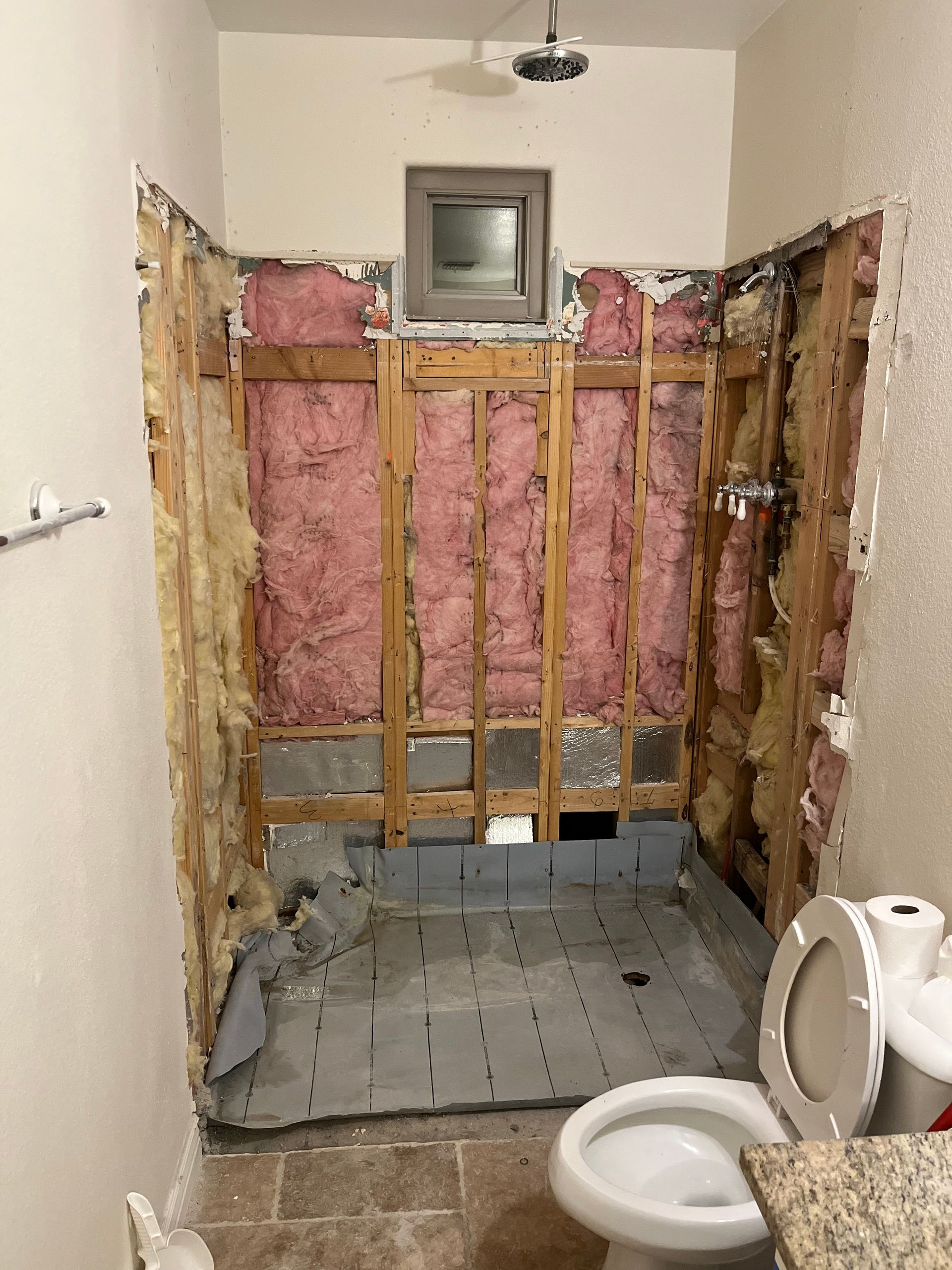 A bathroom with a toilet and a shower being remodeled