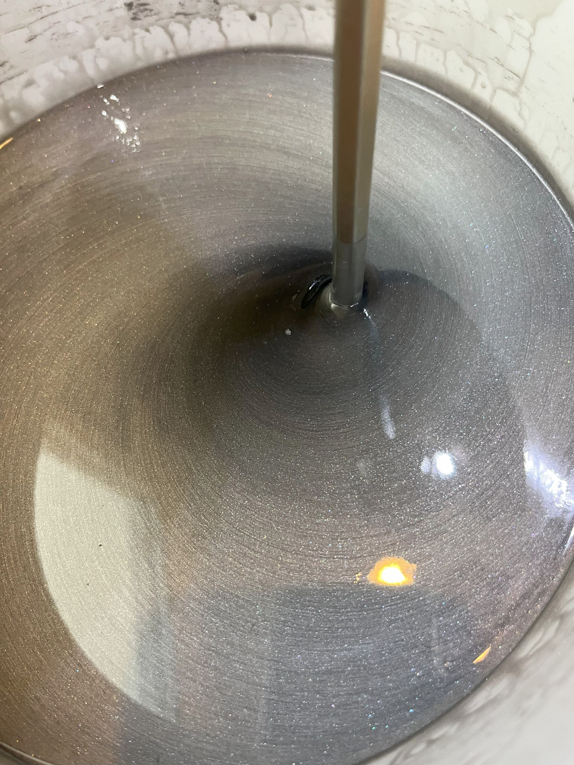 A close up of a bowl of liquid with a spoon in it.