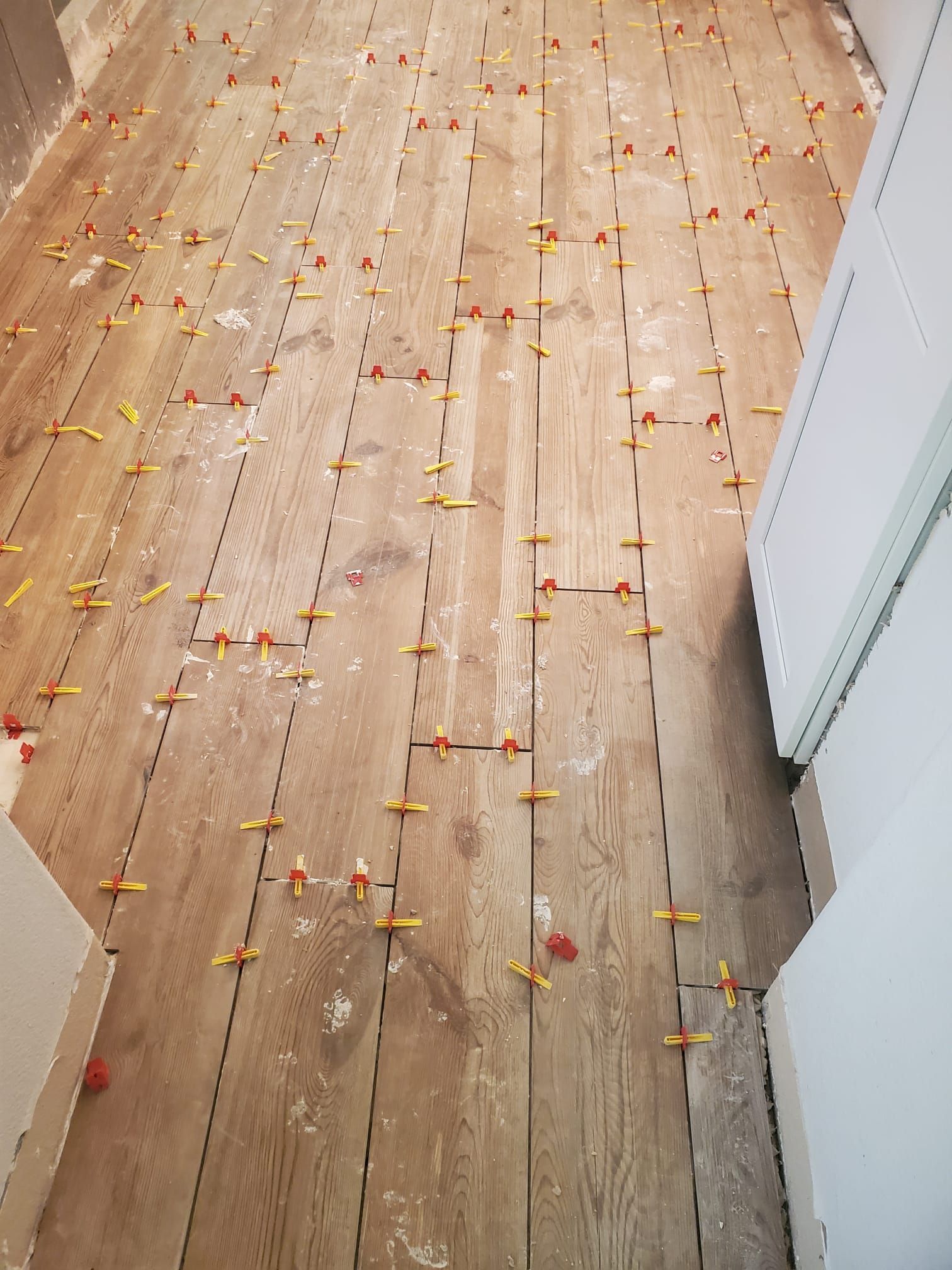 A wooden floor with a lot of tile spacers on it.