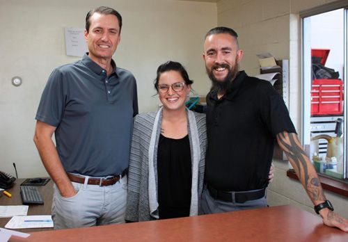 A man and two women are posing for a picture in an office.