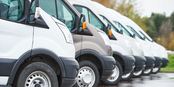 A row of white vans parked next to each other in a parking lot.