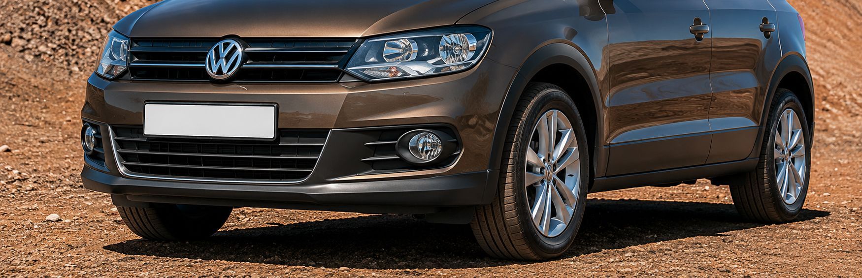 Gray Volkswagen sedan parked on gravel, front view with headlights and grille visible.