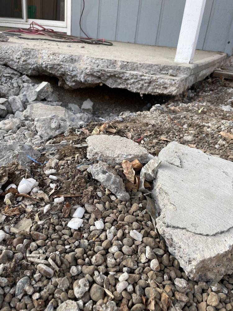 A concrete porch with a lot of rocks in front of it.