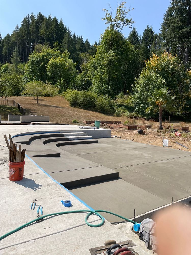 A bucket of brushes sits on a concrete surface next to a hose.