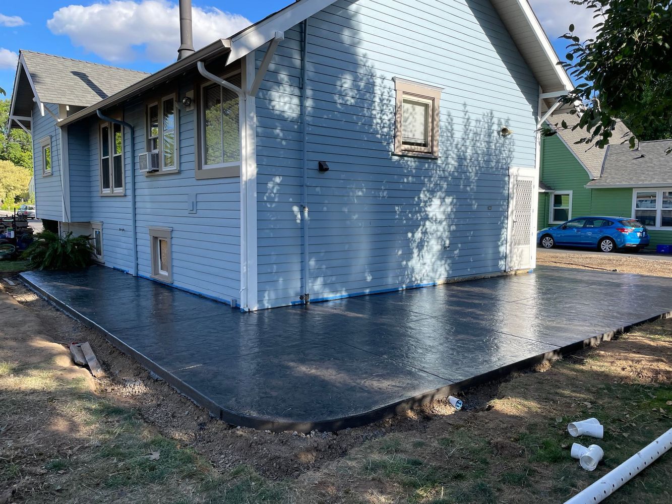 A blue house with a concrete patio in front of it.