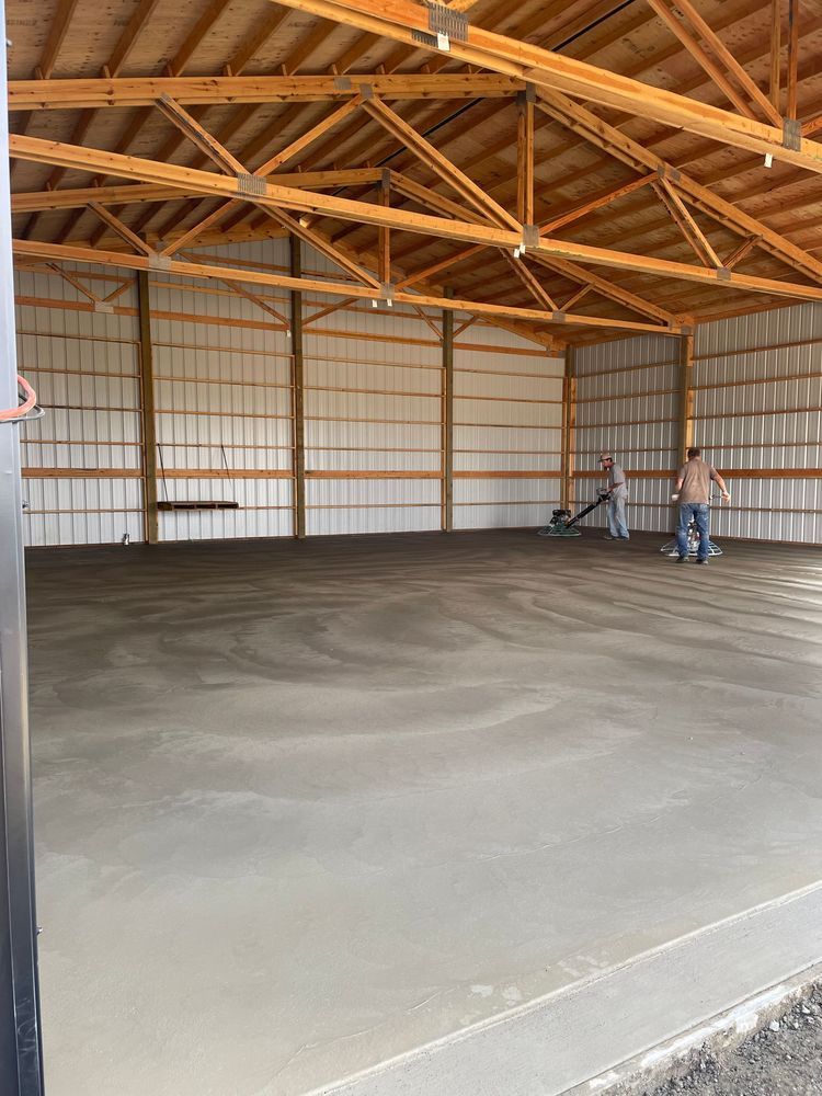 Two men are working on a concrete floor in a large building.