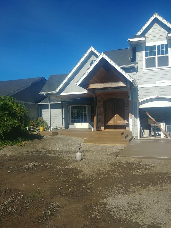 A large white house with a gray roof is being built.