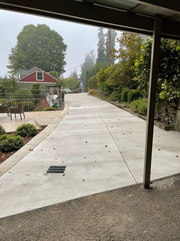 A concrete driveway leading to a red house on a foggy day.
