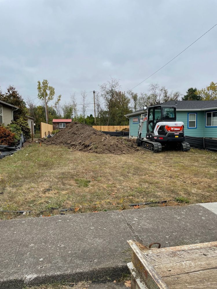 A bulldozer is sitting in the middle of a dirt field next to a house.