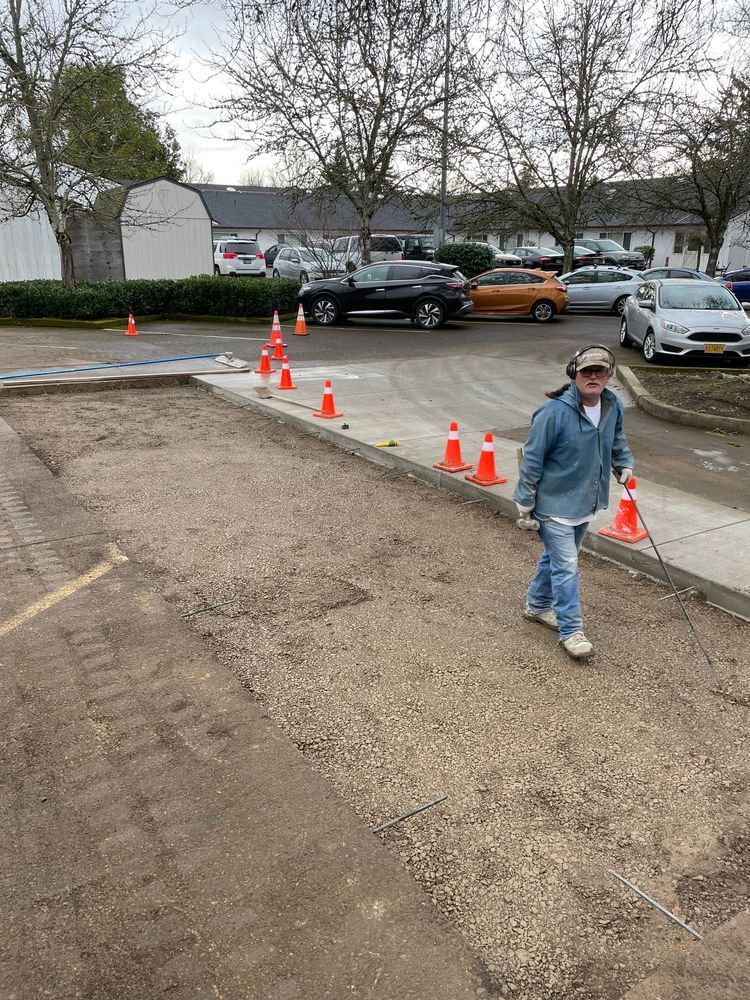 A man is walking down a sidewalk next to a parking lot.