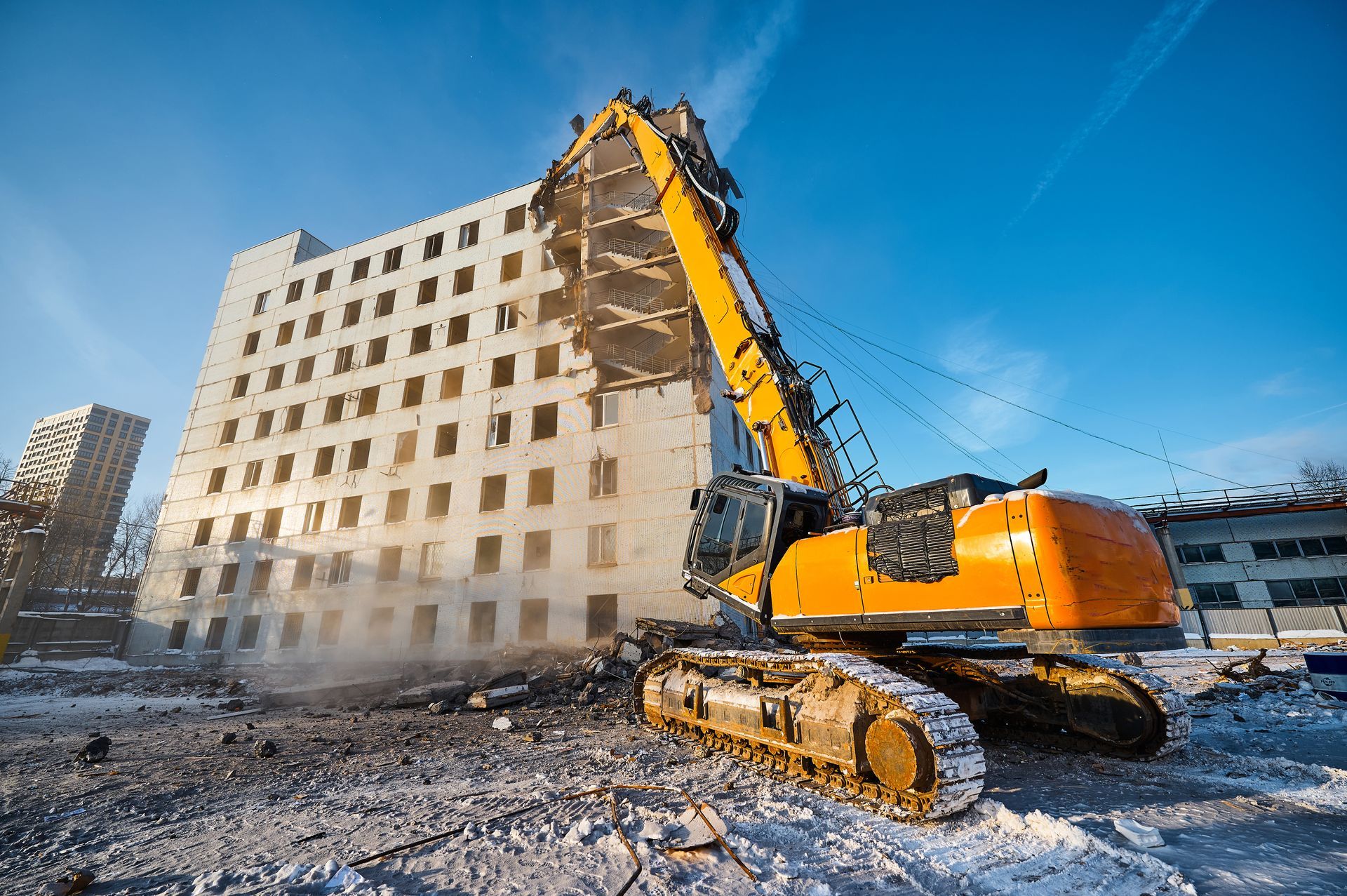 Residential demolition contractor using excavator to tear down large building structure.