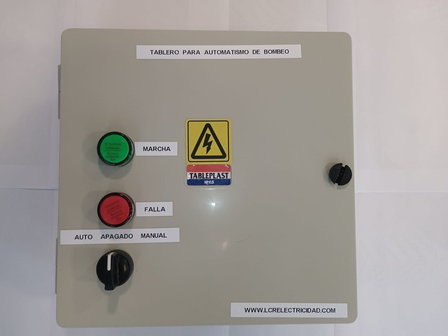 Un panel de control eléctrico con un botón verde, un botón rojo y un interruptor selector automático/manual en una caja gris.