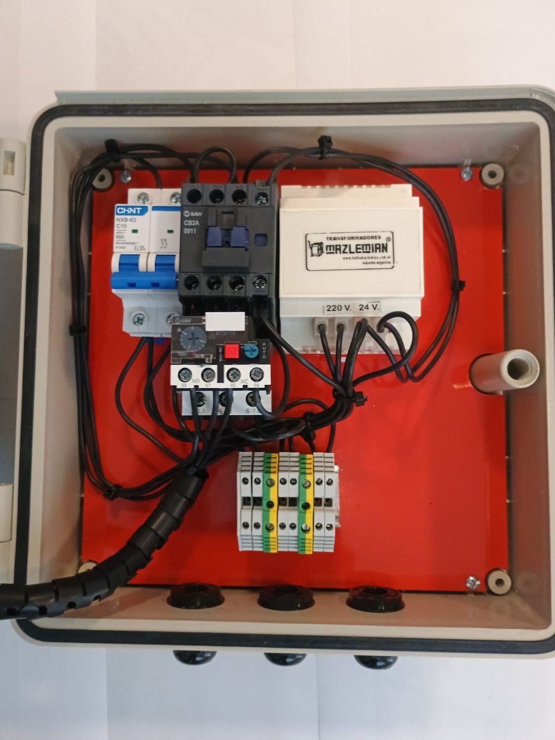 Un panel de control eléctrico con un botón verde, un botón rojo y un interruptor selector automático/manual en una caja gris.