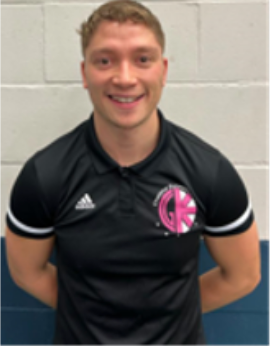 A young man with a beard is smiling for the camera while wearing a brown jacket.