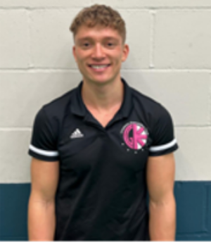 A young man with a beard is smiling for the camera while wearing a brown jacket.