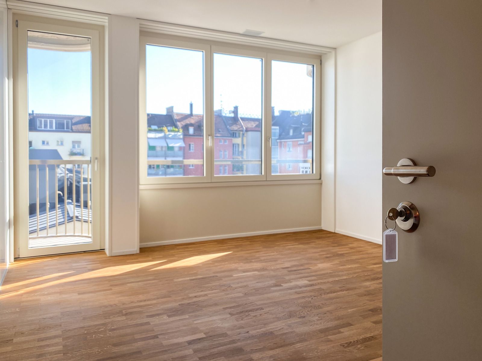 An empty room with hardwood floors and a large window.