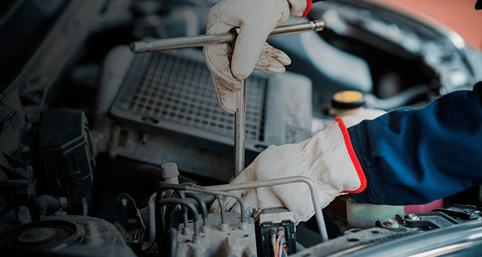 Un mecánico está trabajando en el motor de un automóvil con una llave.