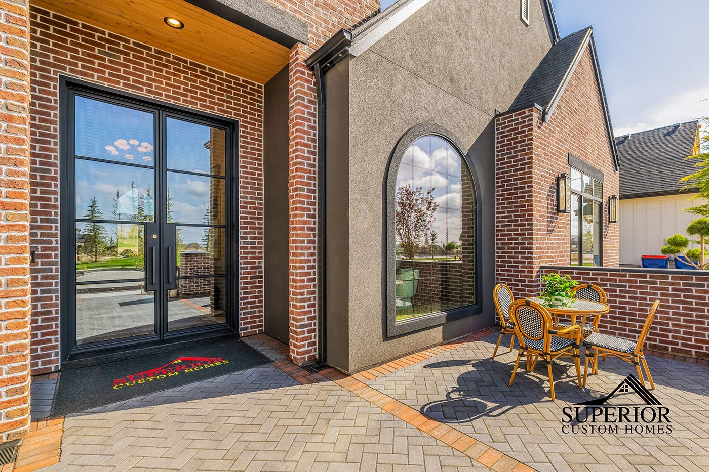A brick house with a patio and a table and chairs in front of it.