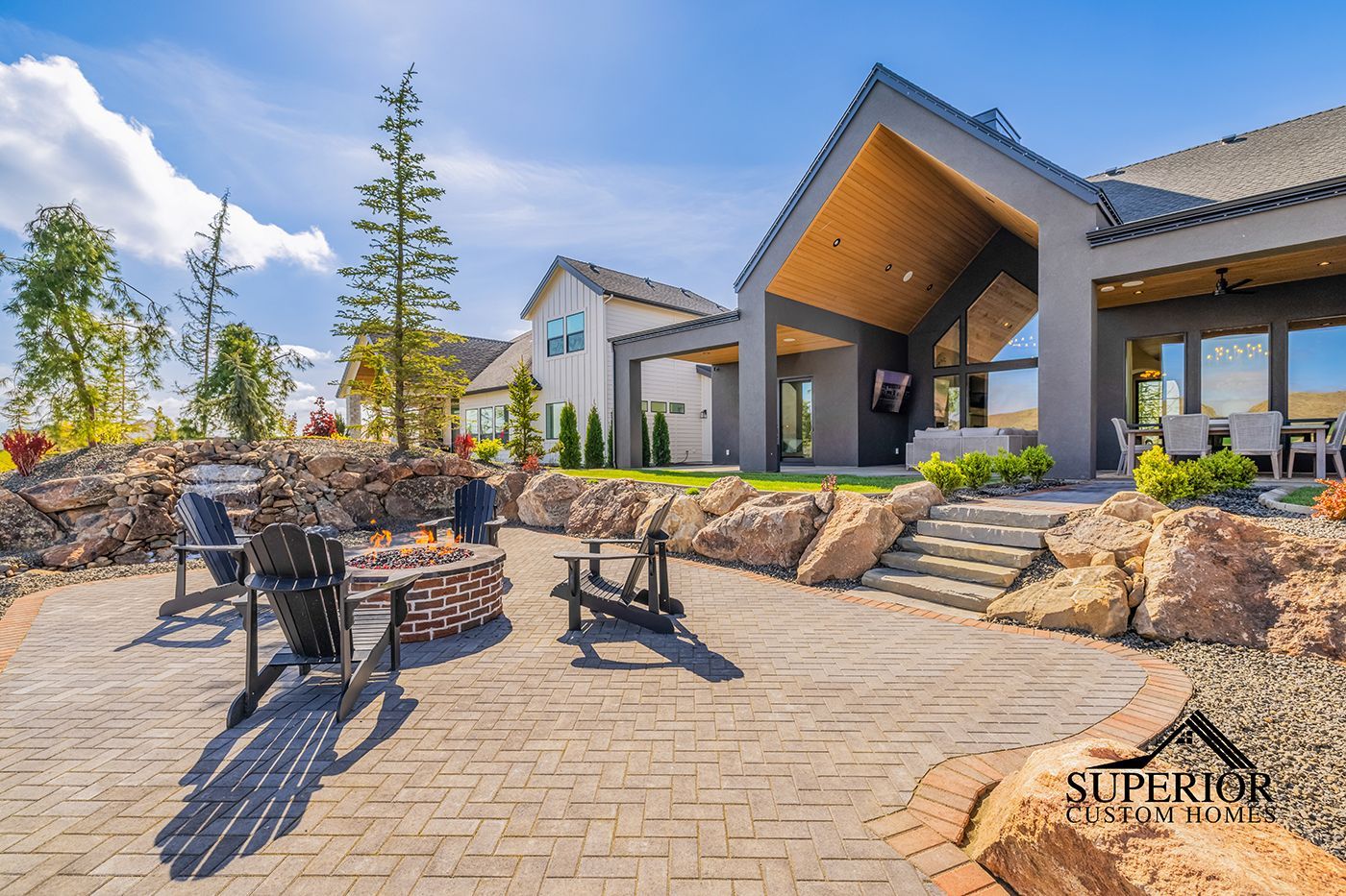 A large house with a fire pit and chairs in front of it.