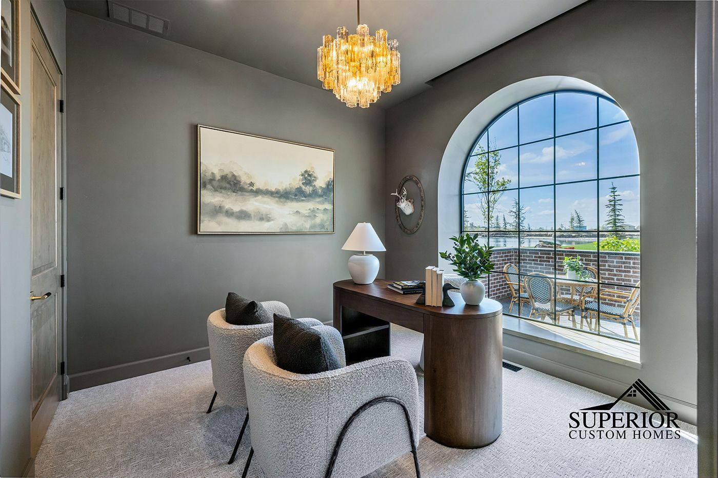 A home office with two chairs , a desk , and a large window.