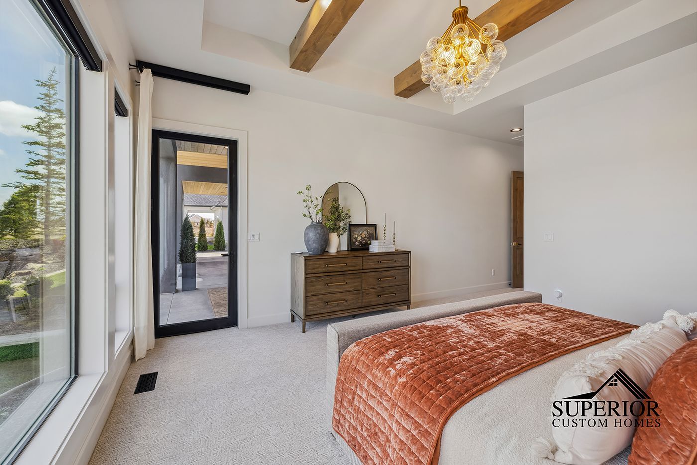A bedroom with a bed , dresser , mirror and window.