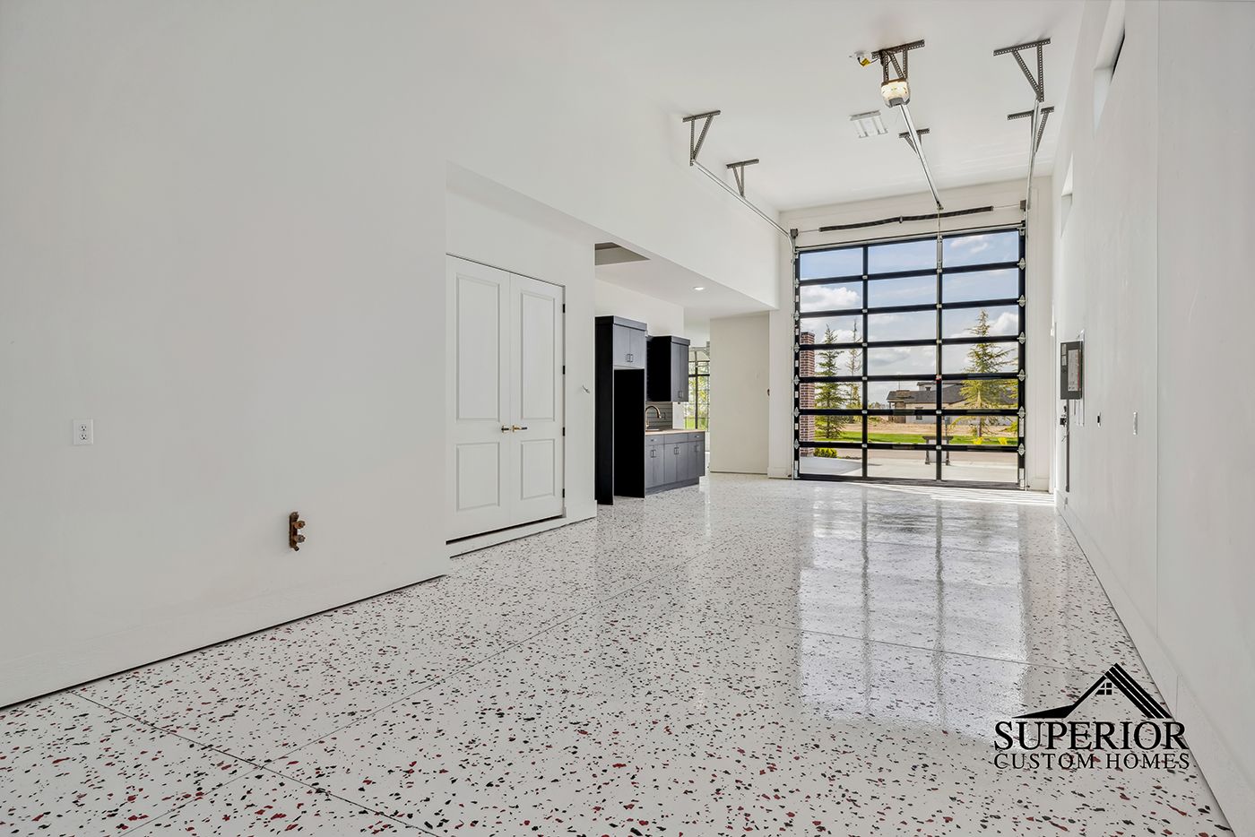 A large empty room with a white floor and a glass garage door.