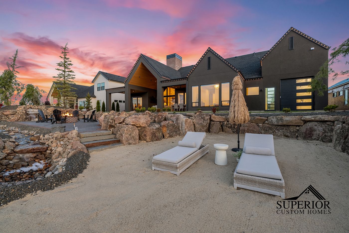 A large house with a patio area and chairs in front of it at sunset.
