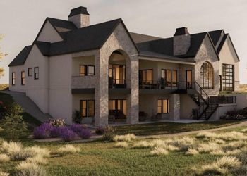Two-story house with a stone facade, multiple windows, a dark roof, and a grassy yard.