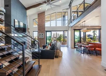 Spacious modern interior with a double-height ceiling, staircase, fireplace, and dining area with an outdoor view.
