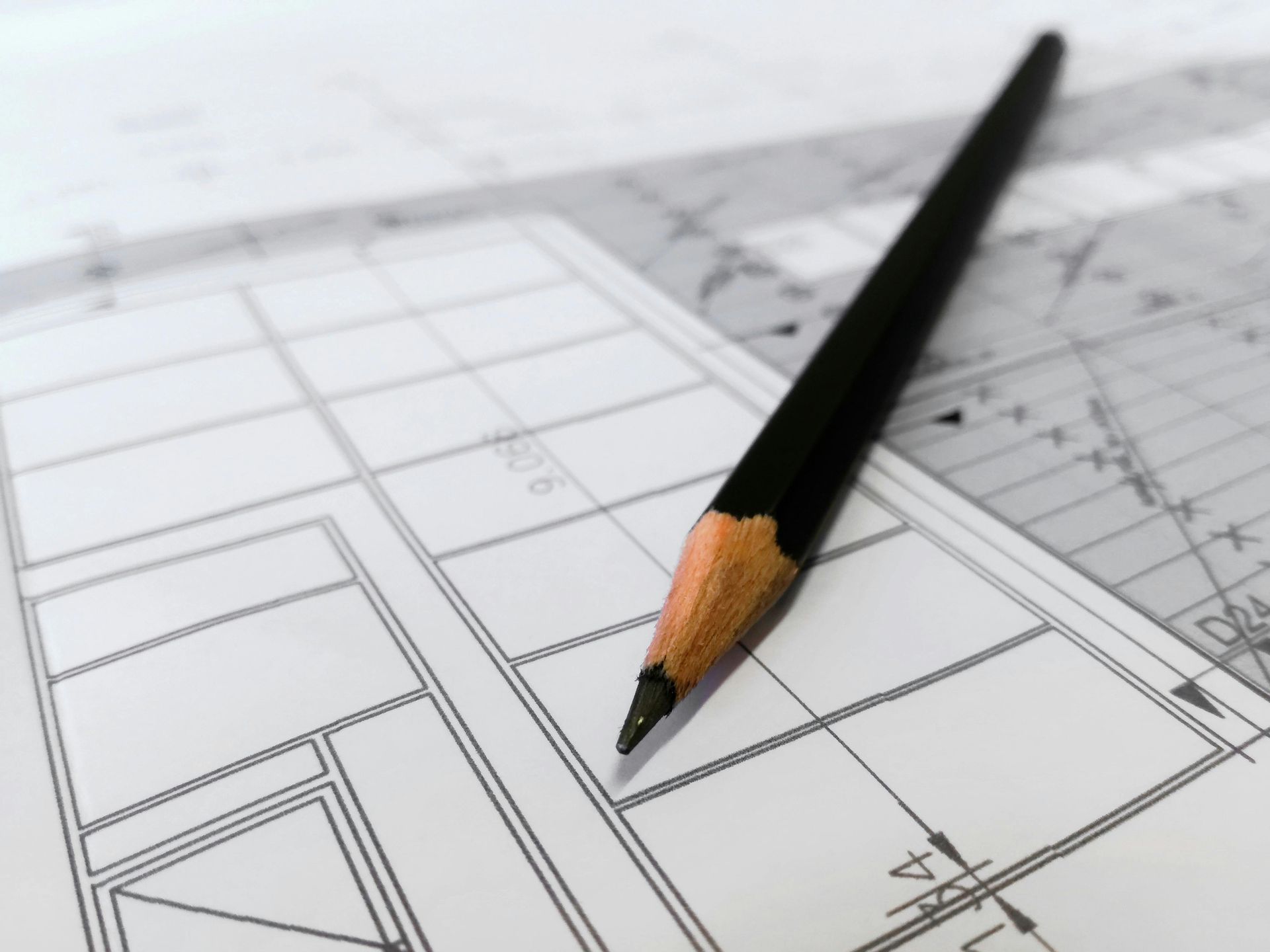 A pencil rests on top of a drawing of a building