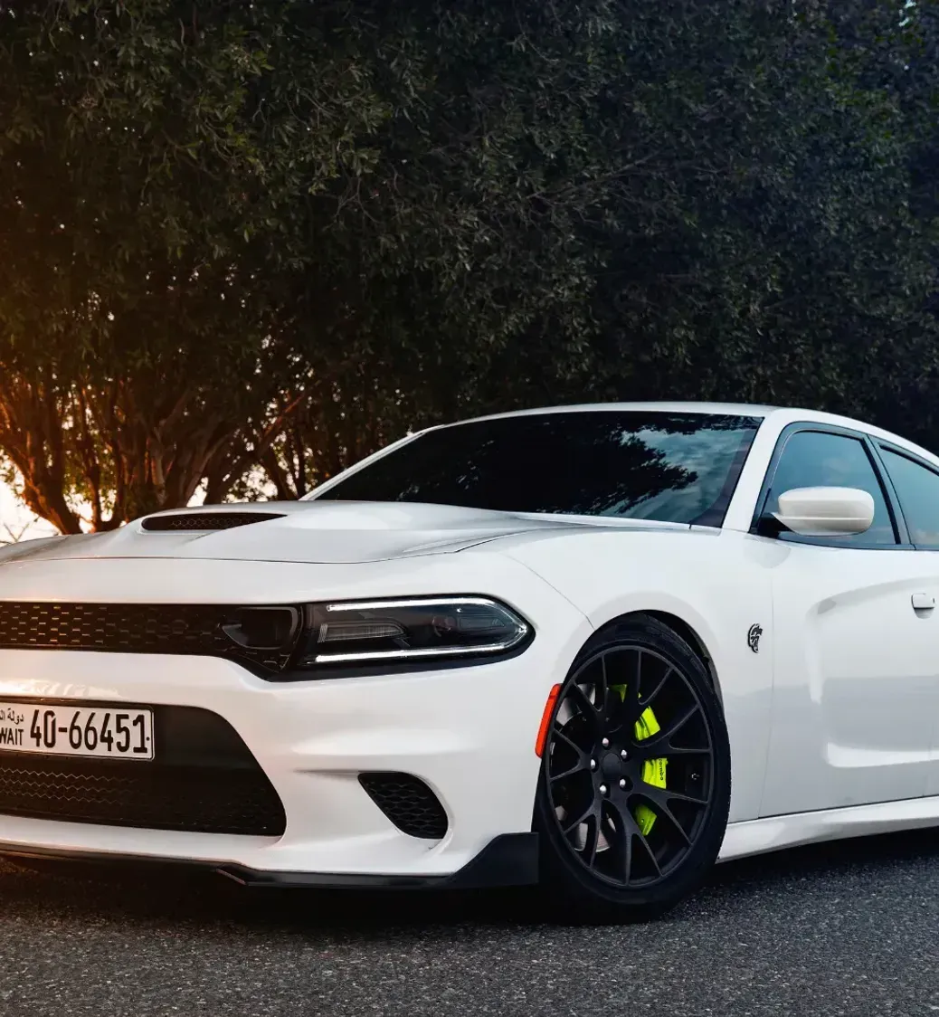 A white dodge charger is parked on the side of the road.