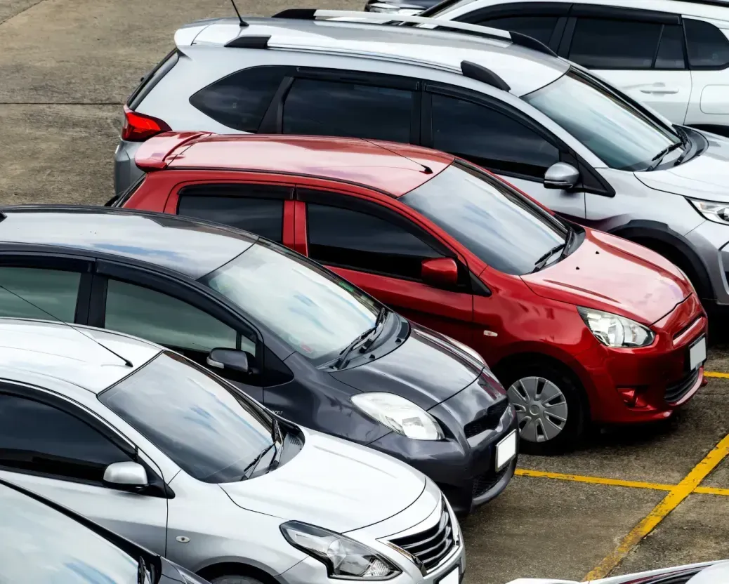 A row of cars are parked in a parking lot.
