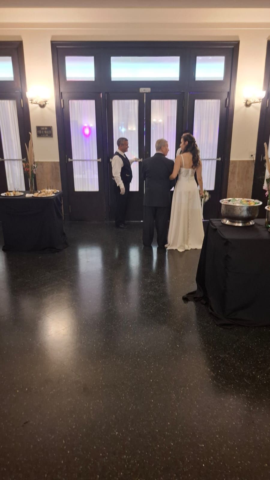 Fiesta nupcial: la novia, el hombre y el acomodador se encuentran frente a las puertas de un salón.