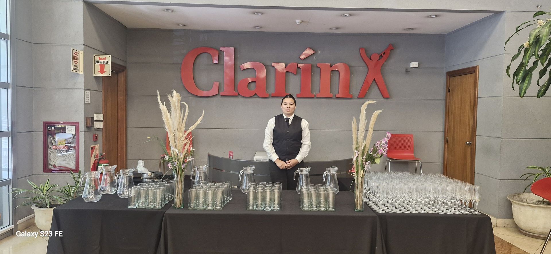 Un camarero está detrás de la barra con vasos y bebidas. El logo