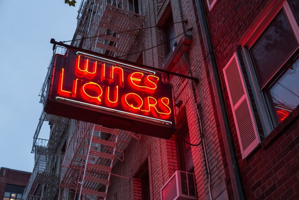 A Neon Sign for Wines Liquors Hangs From the Side of a Building — Sign Media Solutions in Lismore, NSW