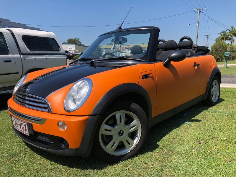 An Orange and Black Convertible Mini Cooper is Parked in the Grass — Sign Media Solutions in Ballina, NSW