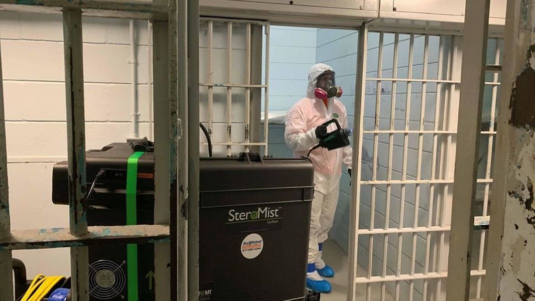 a man in a prison cell using a sterilization mist machine