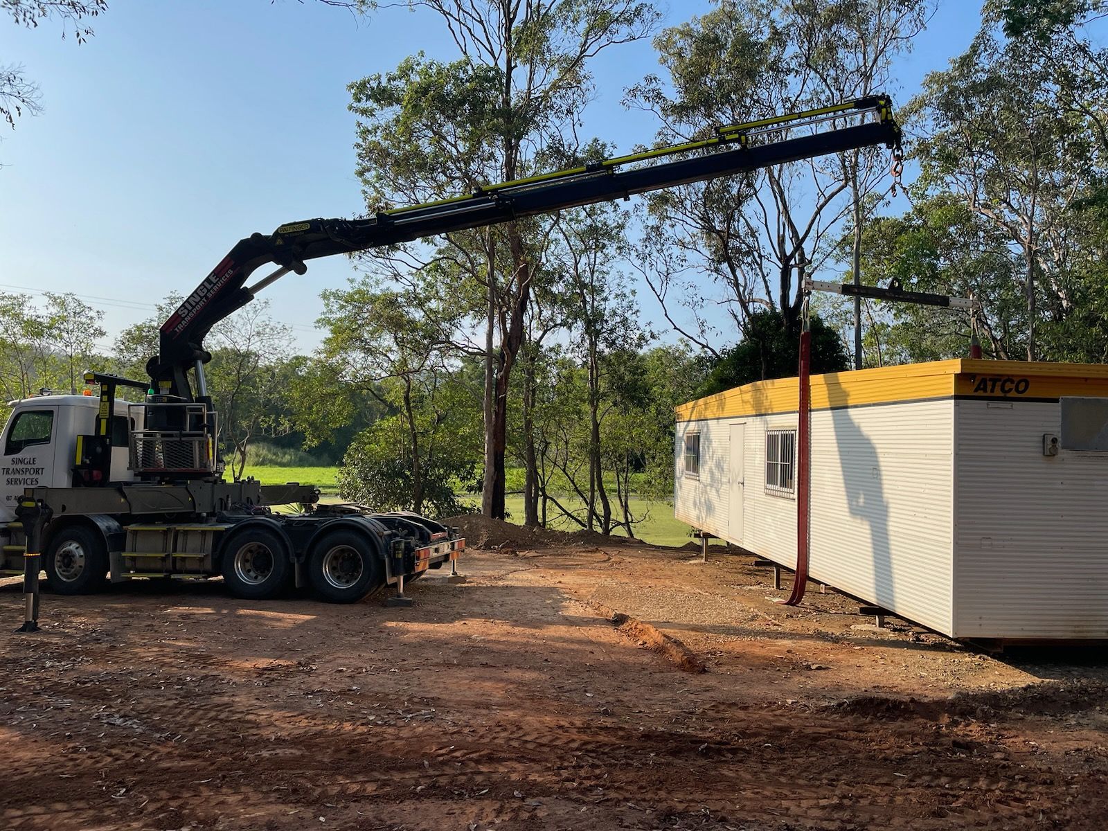 A truck with a crane attached to it is carrying a trailer — Single Transport Services In Palmyra, QLD