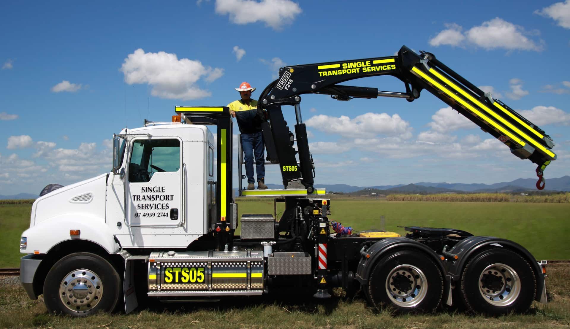 A Man Is Standing On Top Of A Truck With A Crane Attached To It — Single Transport Services In Palmyra, QLD